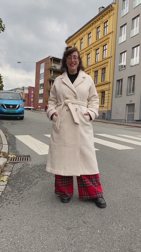 Kremhvit, oversized kåpe fra King Louie. Fire knapper i front, skjortekrage, lommer i front og matchende knytebelte i midja.