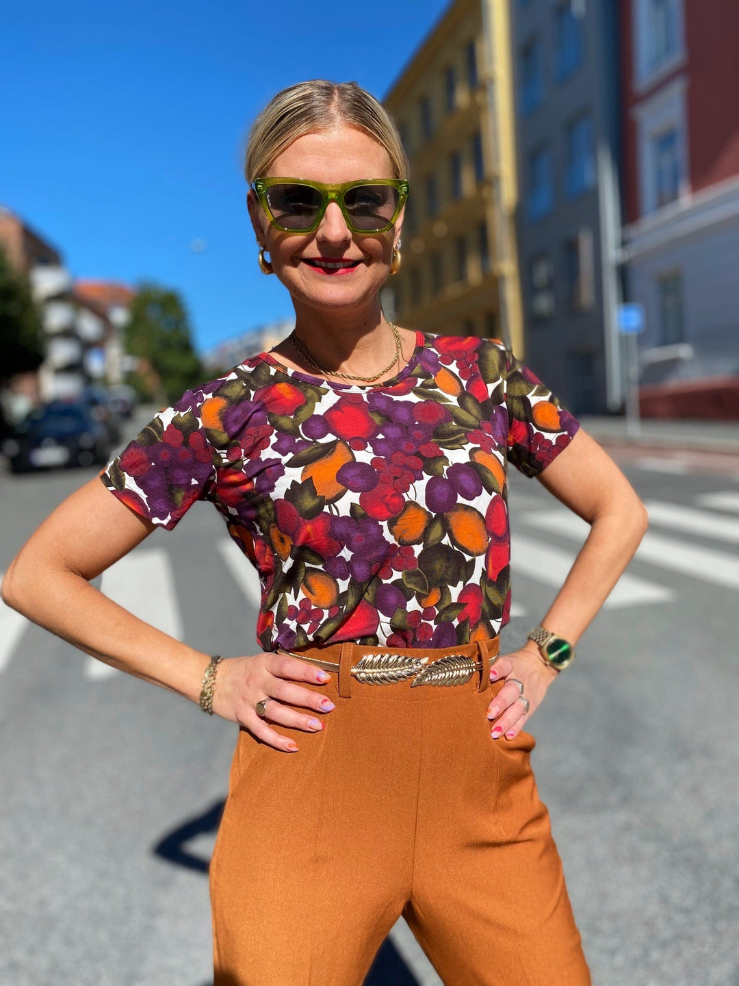 T-skjorte med frukt print fra Dianas Vintage. Hvit bunn med lilla, orange og grønn frukt. Rund hals, korte ermer og kort lengde.