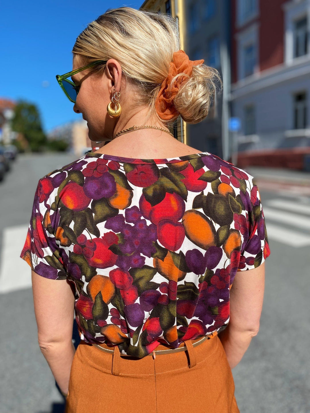 T-skjorte med frukt print fra Dianas Vintage. Hvit bunn med lilla, orange og grønn frukt. Rund hals, korte ermer og kort lengde.