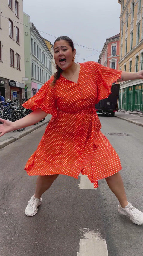 Monika dress short - dots orange fra Dianas Vintage. Rettferdigsydd hos Fair & Square. 100 % Viskose. Nydelig orange kjole med hvite prikker. Lommer, klokkeermer og knapper hele veien.